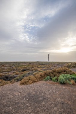 Doğa koruma alanında deniz feneriyle çekilen alacakaranlık manzarası. Gün batımında deniz manzarası. Hafif bir Kalima sırasında deniz feneri, Morro Jable 'da kum fırtınası, Fuerteventura, Kanarya Adaları, İspanya