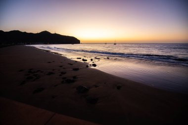 Sabah kumsalda. Güneşin doğuşunda deniz manzarası. Koyun kıyı şeridi, hafif bir kum fırtınası sırasında siyah kumlar, bir Calima. Gran Tarajal, Kanarya Adaları, İspanya
