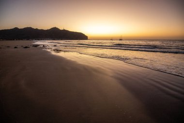 Sabah kumsalda. Güneşin doğuşunda deniz manzarası. Koyun kıyı şeridi, hafif bir kum fırtınası sırasında siyah kumlar, bir Calima. Gran Tarajal, Kanarya Adaları, İspanya