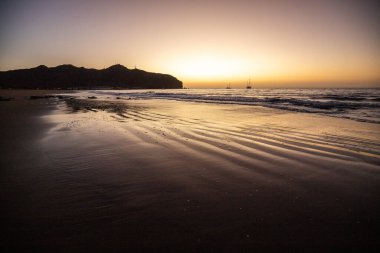 Sabah kumsalda. Güneşin doğuşunda deniz manzarası. Koyun kıyı şeridi, hafif bir kum fırtınası sırasında siyah kumlar, bir Calima. Gran Tarajal, Kanarya Adaları, İspanya