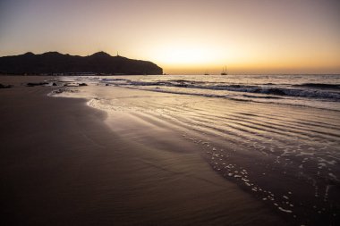 Sabah kumsalda. Güneşin doğuşunda deniz manzarası. Koyun kıyı şeridi, hafif bir kum fırtınası sırasında siyah kumlar, bir Calima. Gran Tarajal, Kanarya Adaları, İspanya