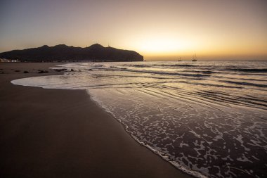 Sabah kumsalda. Güneşin doğuşunda deniz manzarası. Koyun kıyı şeridi, hafif bir kum fırtınası sırasında siyah kumlar, bir Calima. Gran Tarajal, Kanarya Adaları, İspanya