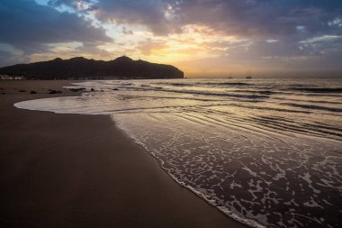 Sabah kumsalda. Güneşin doğuşunda deniz manzarası. Koyun kıyı şeridi, hafif bir kum fırtınası sırasında siyah kumlar, bir Calima. Gran Tarajal, Kanarya Adaları, İspanya