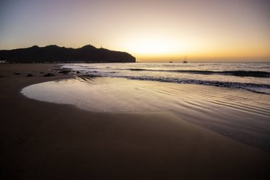 Sabah kumsalda. Güneşin doğuşunda deniz manzarası. Koyun kıyı şeridi, hafif bir kum fırtınası sırasında siyah kumlar, bir Calima. Gran Tarajal, Kanarya Adaları, İspanya