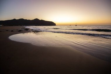 Sabah kumsalda. Güneşin doğuşunda deniz manzarası. Koyun kıyı şeridi, hafif bir kum fırtınası sırasında siyah kumlar, bir Calima. Gran Tarajal, Kanarya Adaları, İspanya