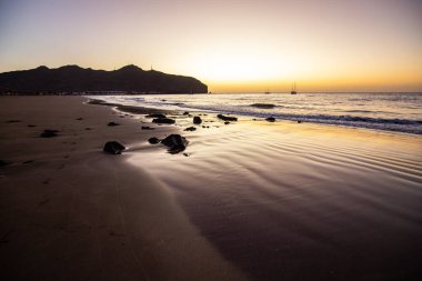 Sabah kumsalda. Güneşin doğuşunda deniz manzarası. Koyun kıyı şeridi, hafif bir kum fırtınası sırasında siyah kumlar, bir Calima. Gran Tarajal, Kanarya Adaları, İspanya