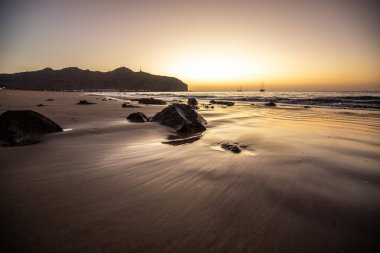 Sabah kumsalda. Güneşin doğuşunda deniz manzarası. Koyun kıyı şeridi, hafif bir kum fırtınası sırasında siyah kumlar, bir Calima. Gran Tarajal, Kanarya Adaları, İspanya