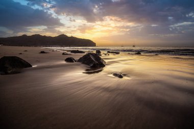 Sabah kumsalda. Güneşin doğuşunda deniz manzarası. Koyun kıyı şeridi, hafif bir kum fırtınası sırasında siyah kumlar, bir Calima. Gran Tarajal, Kanarya Adaları, İspanya