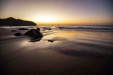Sabah kumsalda. Güneşin doğuşunda deniz manzarası. Koyun kıyı şeridi, hafif bir kum fırtınası sırasında siyah kumlar, bir Calima. Gran Tarajal, Kanarya Adaları, İspanya