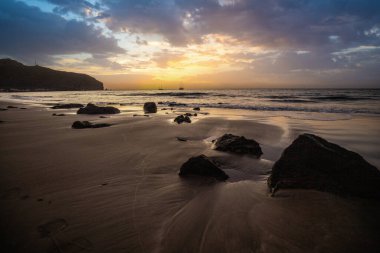 Sabah kumsalda. Güneşin doğuşunda deniz manzarası. Koyun kıyı şeridi, hafif bir kum fırtınası sırasında siyah kumlar, bir Calima. Gran Tarajal, Kanarya Adaları, İspanya