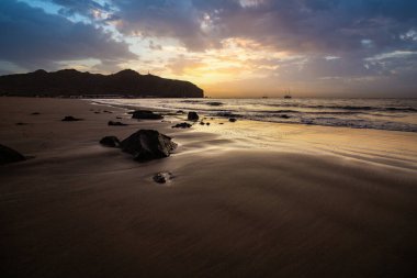 Sabah kumsalda. Güneşin doğuşunda deniz manzarası. Koyun kıyı şeridi, hafif bir kum fırtınası sırasında siyah kumlar, bir Calima. Gran Tarajal, Kanarya Adaları, İspanya