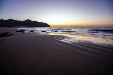 Sabah kumsalda. Güneşin doğuşunda deniz manzarası. Koyun kıyı şeridi, hafif bir kum fırtınası sırasında siyah kumlar, bir Calima. Gran Tarajal, Kanarya Adaları, İspanya