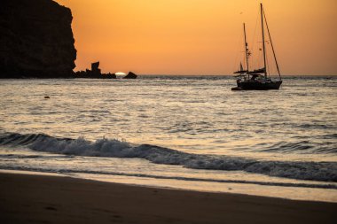 Fırtına sırasında gün doğumu, Calima. Sis kaplı ufuk turuncuya dönerken güneş bir güneş topu gibi doğuyor. Bir tekne denize demir attı. Gran Tarajal 'daki manzara fotoğrafı, Kanarya Adaları, İspanya