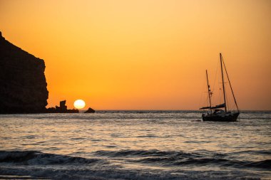 Fırtına sırasında gün doğumu, Calima. Sis kaplı ufuk turuncuya dönerken güneş bir güneş topu gibi doğuyor. Bir tekne denize demir attı. Gran Tarajal 'daki manzara fotoğrafı, Kanarya Adaları, İspanya