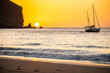 Fırtına sırasında gün doğumu, Calima. Sis kaplı ufuk turuncuya dönerken güneş bir güneş topu gibi doğuyor. Bir tekne denize demir attı. Gran Tarajal 'daki manzara fotoğrafı, Kanarya Adaları, İspanya