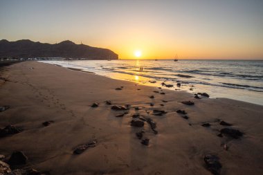 Sabah kumsalda. Güneşin doğuşunda deniz manzarası. Koyun kıyı şeridi, hafif bir kum fırtınası sırasında siyah kumlar, bir Calima. Gran Tarajal, Kanarya Adaları, İspanya