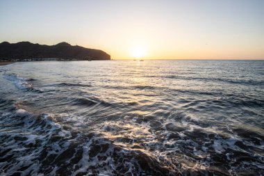 Sabah kumsalda. Güneşin doğuşunda deniz manzarası. Koyun kıyı şeridi, hafif bir kum fırtınası sırasında siyah kumlar, bir Calima. Gran Tarajal, Kanarya Adaları, İspanya