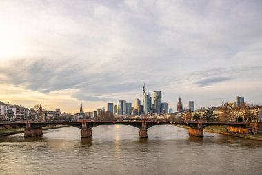 Gün batımında büyük bir şehir. Nehrin ufuk çizgisi üzerinde modern binalar. Yüksek binalar suya yansıtılır. Frankfurt am Main, Almanya 'nın modern mimarisi