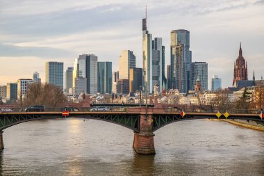 Gün batımında büyük bir şehir. Nehrin ufuk çizgisi üzerinde modern binalar. Yüksek binalar suya yansıtılır. Frankfurt am Main, Almanya 'nın modern mimarisi