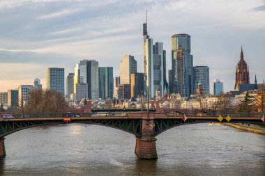 Gün batımında büyük bir şehir. Nehrin ufuk çizgisi üzerinde modern binalar. Yüksek binalar suya yansıtılır. Frankfurt am Main, Almanya 'nın modern mimarisi