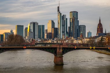 Gün batımında büyük bir şehir. Nehrin ufuk çizgisi üzerinde modern binalar. Yüksek binalar suya yansıtılır. Frankfurt am Main, Almanya 'nın modern mimarisi