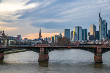 Gün batımında büyük bir şehir. Nehrin ufuk çizgisi üzerinde modern binalar. Yüksek binalar suya yansıtılır. Frankfurt am Main, Almanya 'nın modern mimarisi