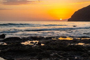 Fırtına sırasında gün batımı, Calima. Güneş bir güneş topu gibi batarken ufukta beliren sis turuncuya döner. Gran Tarajal, Kanarya Adaları, İspanya 'da volkanik plaj manzarası