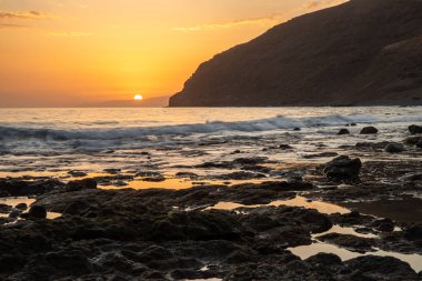 Fırtına sırasında gün batımı, Calima. Güneş bir güneş topu gibi batarken ufukta beliren sis turuncuya döner. Gran Tarajal, Kanarya Adaları, İspanya 'da volkanik plaj manzarası