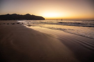 Sabah kumsalda. Güneşin doğuşunda deniz manzarası. Koyun kıyı şeridi, hafif bir kum fırtınası sırasında siyah kumlar, bir Calima. Gran Tarajal, Kanarya Adaları, İspanya