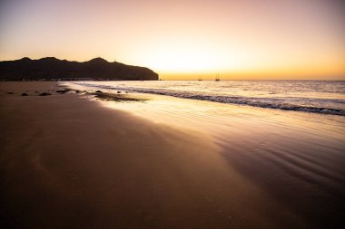 Sabah kumsalda. Güneşin doğuşunda deniz manzarası. Koyun kıyı şeridi, hafif bir kum fırtınası sırasında siyah kumlar, bir Calima. Gran Tarajal, Kanarya Adaları, İspanya