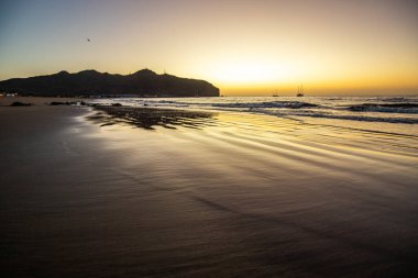 Sabah kumsalda. Güneşin doğuşunda deniz manzarası. Koyun kıyı şeridi, hafif bir kum fırtınası sırasında siyah kumlar, bir Calima. Gran Tarajal, Kanarya Adaları, İspanya
