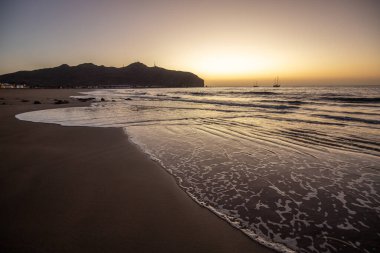 Sabah kumsalda. Güneşin doğuşunda deniz manzarası. Koyun kıyı şeridi, hafif bir kum fırtınası sırasında siyah kumlar, bir Calima. Gran Tarajal, Kanarya Adaları, İspanya