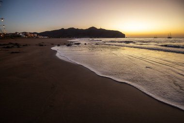 Sabah kumsalda. Güneşin doğuşunda deniz manzarası. Koyun kıyı şeridi, hafif bir kum fırtınası sırasında siyah kumlar, bir Calima. Gran Tarajal, Kanarya Adaları, İspanya