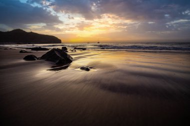 Sabah kumsalda. Güneşin doğuşunda deniz manzarası. Koyun kıyı şeridi, hafif bir kum fırtınası sırasında siyah kumlar, bir Calima. Gran Tarajal, Kanarya Adaları, İspanya