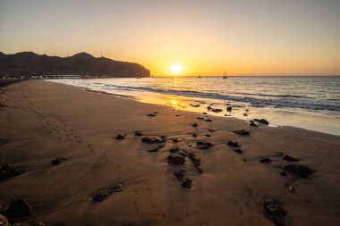 Sabah kumsalda. Güneşin doğuşunda deniz manzarası. Koyun kıyı şeridi, hafif bir kum fırtınası sırasında siyah kumlar, bir Calima. Gran Tarajal, Kanarya Adaları, İspanya