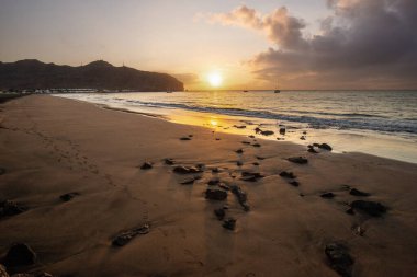 Sabah kumsalda. Güneşin doğuşunda deniz manzarası. Koyun kıyı şeridi, hafif bir kum fırtınası sırasında siyah kumlar, bir Calima. Gran Tarajal, Kanarya Adaları, İspanya