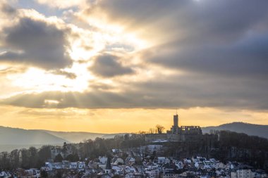 Bakış açısı ve manzara akşam üstü gün batımında çekiliyor. Kale manzarasında soğuk hava ve hafif kar. Şatoya ve kışın Frankfurt Knigstein, Taunus, Hesse, Almanya yakınlarındaki bir köye bakın.