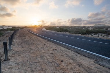 Kumulların arasında bir yolda güzel bir sabah. Bulutlu bir yolda gün doğumu. Corralejo Ulusal Parkı, Kanarya Adaları, İspanya