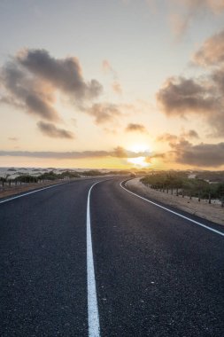 Kumulların arasında bir yolda güzel bir sabah. Bulutlu bir yolda gün doğumu. Corralejo Ulusal Parkı, Kanarya Adaları, İspanya