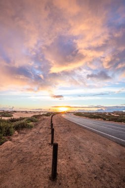 Kumulların arasında bir yolda güzel bir sabah. Bulutlu bir yolda gün doğumu. Corralejo Ulusal Parkı, Kanarya Adaları, İspanya