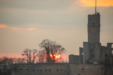 Knigstein castle ruins at sunset. Viewpoint with a view over a village to a ruin in winter, in the background you can see a sunset. Landscape photo of Knigstein im Taunus, Hesse, Germany clipart