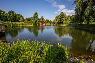 Beautiful summer evening in a park. Landscape shot in Krishna valley at sunset. Park and temple complex at Balaton, Unagrn clipart