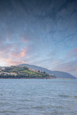 Arka planda tepeler olan sahil ve deniz güney İtalya 'da tatil köyü olan körfez ve kıyı.