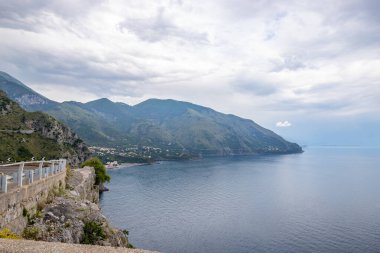 Kıyı manzarası fotoğrafı. Deniz boyunca uzanan ve çarpıcı yeşil Akdeniz manzarası boyunca uzanan bir yoldan manzara. Salerno, İtalya kıyıları