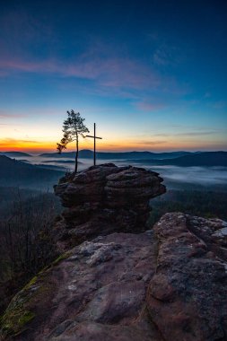 Zirve, ormanın ortasında bir kumtaşı kayası üzerinde kesişiyor. Sis kaplı bir ormanın üzerindeki muhteşem manzaralı manzara. Almanya 'nın Derebeyi Ormanı' nda Gün Doğumu