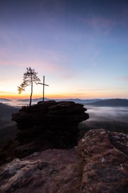 Zirve, ormanın ortasında bir kumtaşı kayası üzerinde kesişiyor. Sis kaplı bir ormanın üzerindeki muhteşem manzaralı manzara. Almanya 'nın Derebeyi Ormanı' nda Gün Doğumu