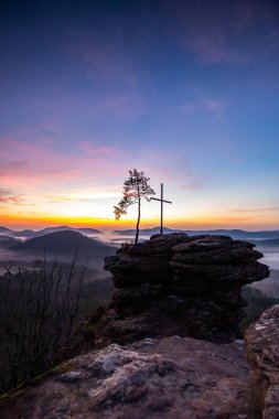Zirve, ormanın ortasında bir kumtaşı kayası üzerinde kesişiyor. Sis kaplı bir ormanın üzerindeki muhteşem manzaralı manzara. Almanya 'nın Derebeyi Ormanı' nda Gün Doğumu