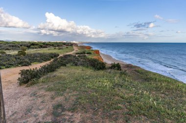 Atlantik Okyanusu 'nda çarpıcı oluşumları olan kayalıklar. Manzara çekiminde sıcak gün batımı. Sahilde ve denizde çarpıcı oluşumlara sahip kızıl kayalıklar, Praia da Falsia, Algarve, Portekiz