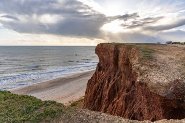 Atlantik Okyanusu 'nda çarpıcı oluşumları olan kayalıklar. Manzara çekiminde sıcak gün batımı. Sahilde ve denizde çarpıcı oluşumlara sahip kızıl kayalıklar, Praia da Falsia, Algarve, Portekiz