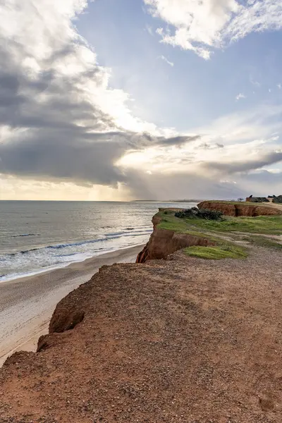 Atlantik Okyanusu 'nda çarpıcı oluşumları olan kayalıklar. Manzara çekiminde sıcak gün batımı. Sahilde ve denizde çarpıcı oluşumlara sahip kızıl kayalıklar, Praia da Falsia, Algarve, Portekiz
